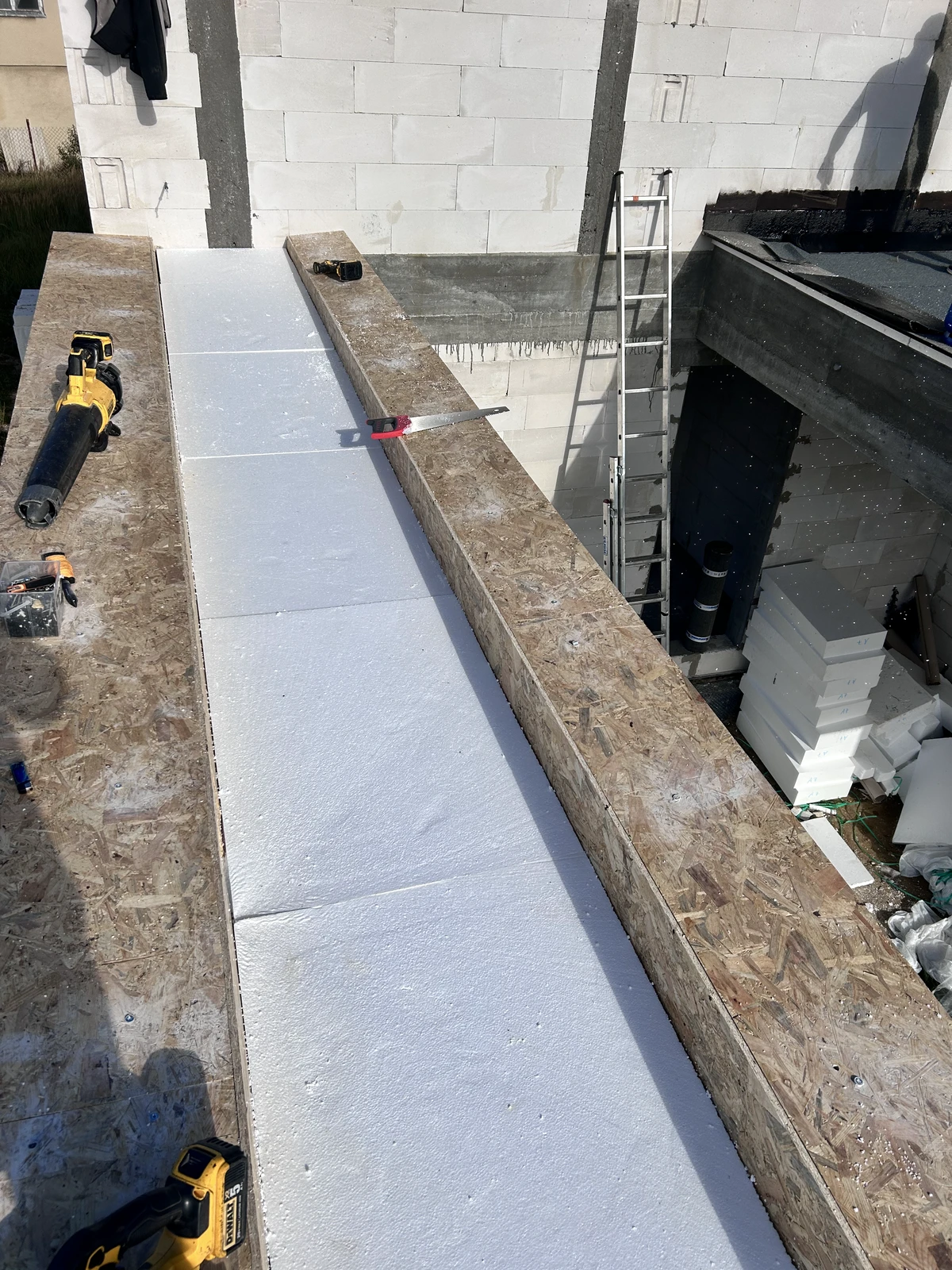 Układanie płyt styropianowych na stropodachu w ramach termoizolacji z narzędziami dekarskimi